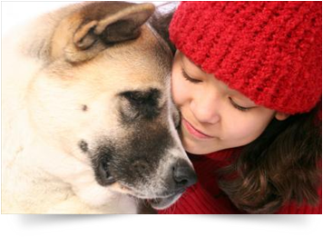 girl in red hat hugging a dog